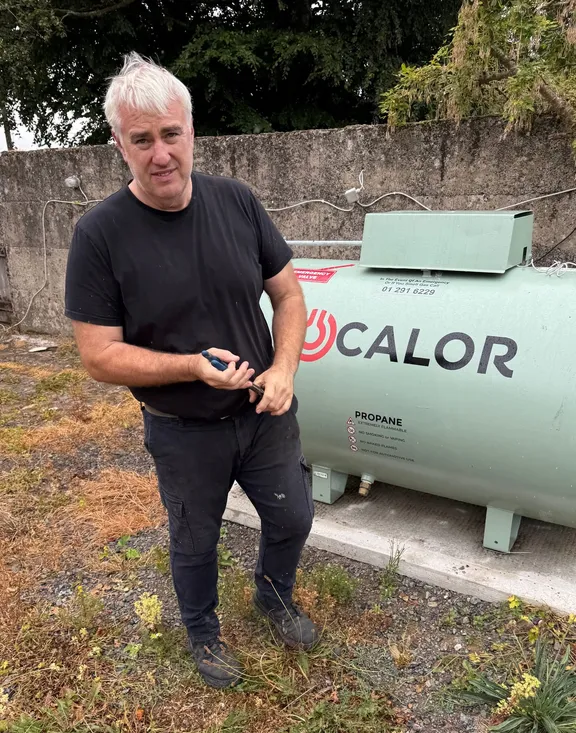 Frank Kelly beside a Calor LPG tank at a house near Charleville