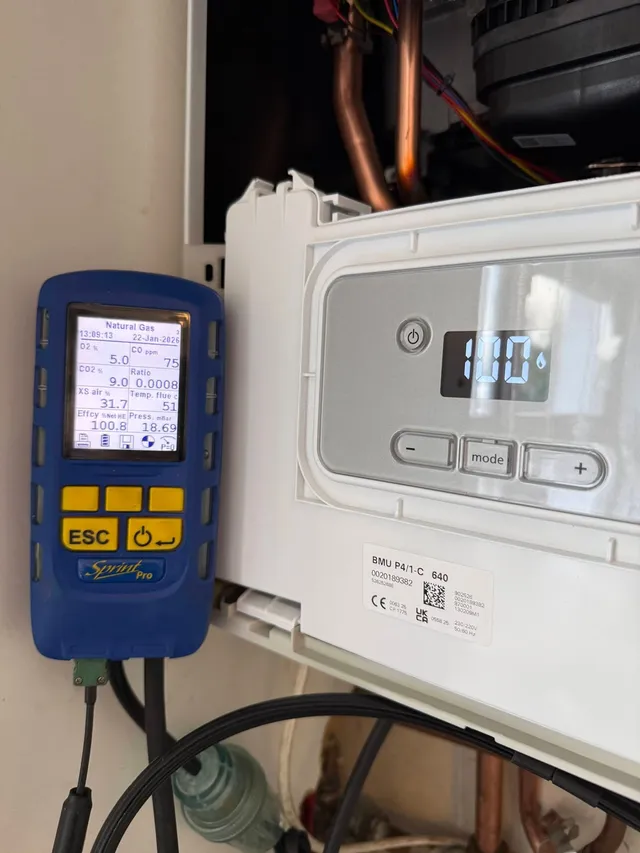 A flue gas analyser in use on an open gas boiler during a service